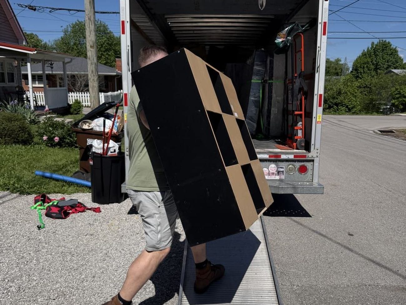 A crew member carrying a large cabinet up the ramp into the box truck.