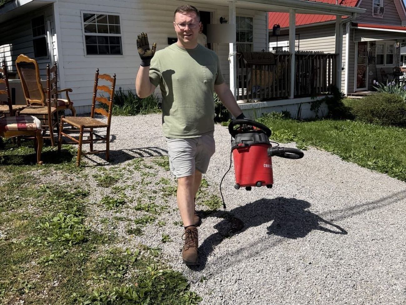 A crew member carrying the shop vacuum out after cleaning up the work area.